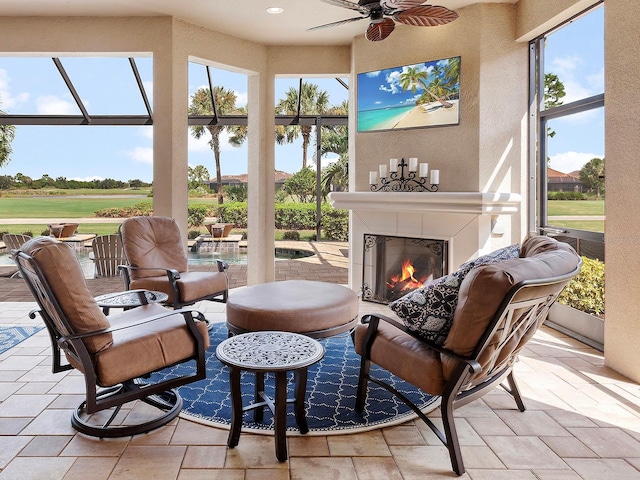 sunroom with plenty of natural light, exterior fireplace, and ceiling fan