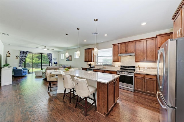 7572 Viola Loop, Lakewood Ranch, FL 34202 - kitchen with appliances with stainless steel finishes, open floor plan, a kitchen island, under cabinet range hood, and dark wood-style flooring