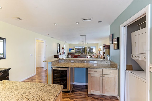 kitchen with dark hardwood / wood-style flooring, wine cooler, light brown cabinetry, and stacked washer and clothes dryer