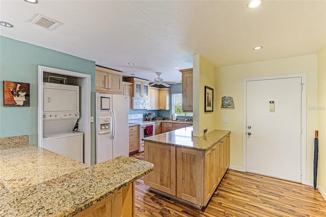 kitchen featuring light stone counters, white appliances, kitchen peninsula, light wood-type flooring, and stacked washer / dryer