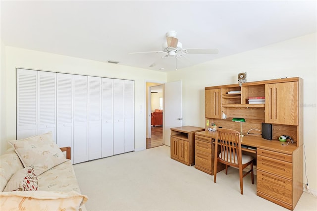 carpeted home office with ceiling fan and built in desk