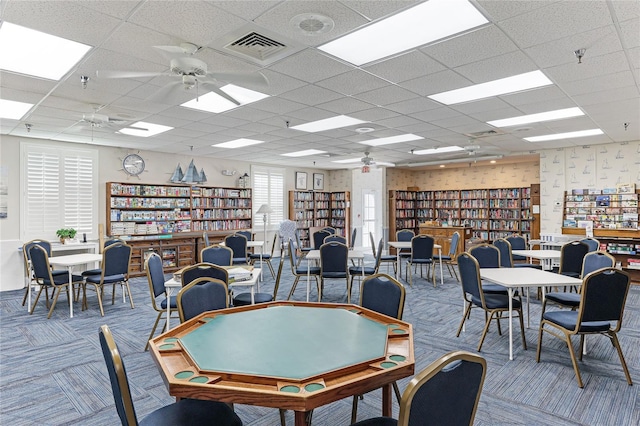 recreation room featuring carpet flooring, ceiling fan, and a drop ceiling