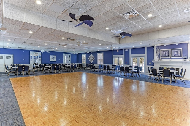 gym with ceiling fan, a drop ceiling, and parquet floors