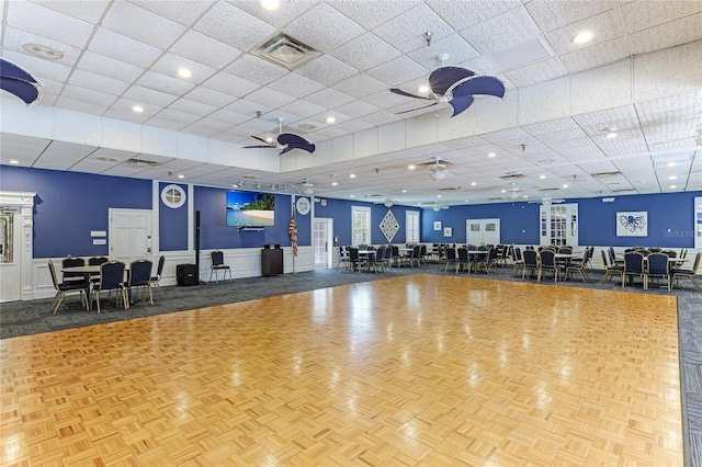 workout area with ceiling fan, a drop ceiling, and parquet floors