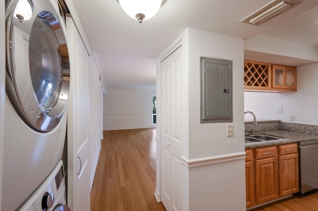 interior space featuring stacked washer / drying machine, electric panel, sink, stainless steel dishwasher, and light hardwood / wood-style floors