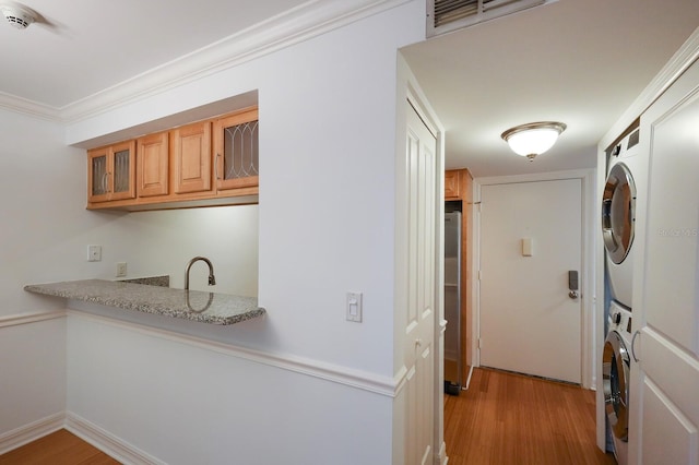 interior space with stacked washer / dryer, stainless steel refrigerator, light hardwood / wood-style floors, and ornamental molding