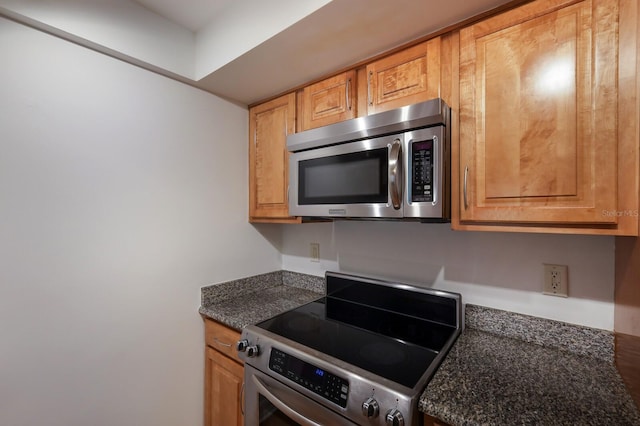 kitchen featuring dark stone counters and stainless steel appliances