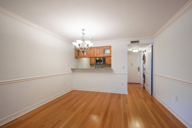 unfurnished living room with light hardwood / wood-style flooring, ornamental molding, and an inviting chandelier