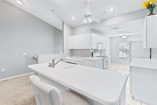 kitchen with white appliances, a sink, white cabinets, light countertops, and a center island with sink