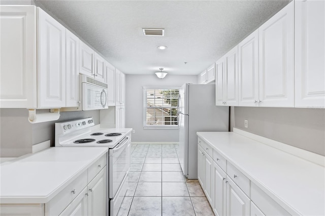 kitchen with white appliances, light countertops, and white cabinetry