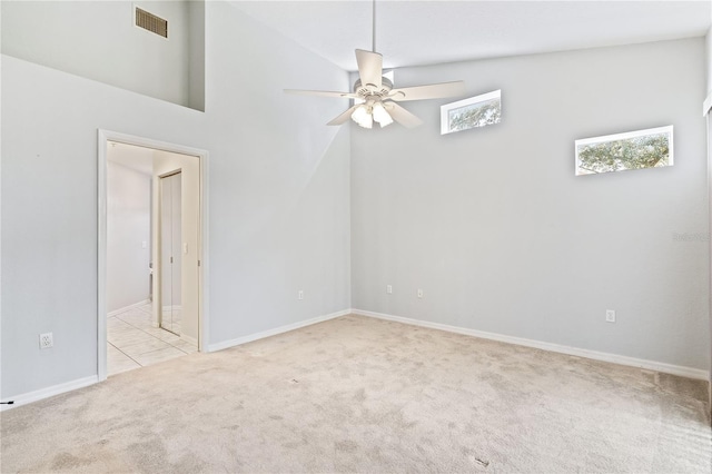 spare room featuring baseboards, visible vents, a ceiling fan, and light colored carpet