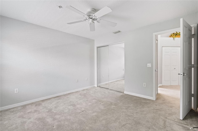 unfurnished bedroom with light carpet, a ceiling fan, visible vents, baseboards, and a closet