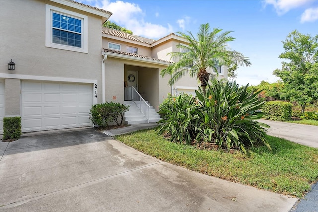 view of front of home with a garage, driveway, a tiled roof, and stucco siding