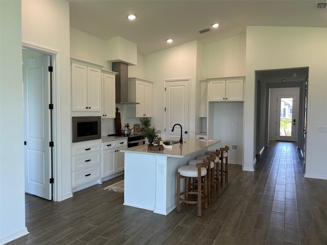 11709 Capstan Pl, Parrish, FL 34219 - kitchen featuring wall chimney range hood, white cabinets, a kitchen island with sink, dark wood-style floors, and high vaulted ceiling