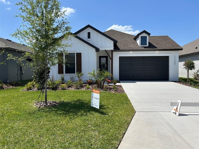 11709 Capstan Pl, Parrish, FL 34219 - modern inspired farmhouse with board and batten siding, a garage, concrete driveway, a front lawn, and roof with shingles