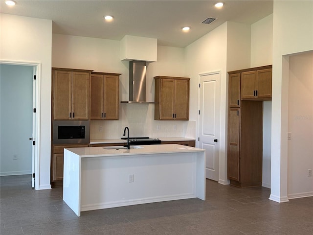 11718 Capstan Pl, Parrish, FL 34219 - kitchen featuring wall chimney exhaust hood, a sink, stainless steel microwave, a center island with sink, and brown cabinetry