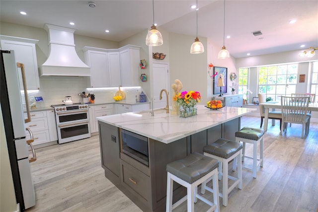 kitchen featuring premium range hood, light hardwood / wood-style flooring, white appliances, and white cabinetry