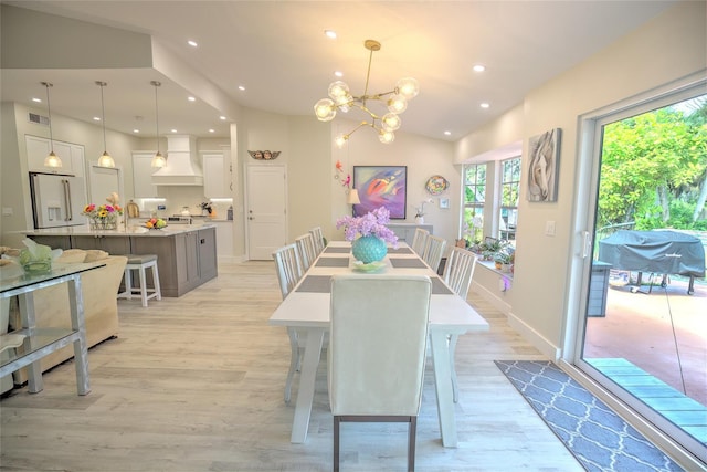 dining area with an inviting chandelier, vaulted ceiling, and light hardwood / wood-style floors