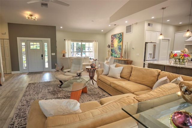 living room featuring lofted ceiling, ceiling fan, and light hardwood / wood-style flooring