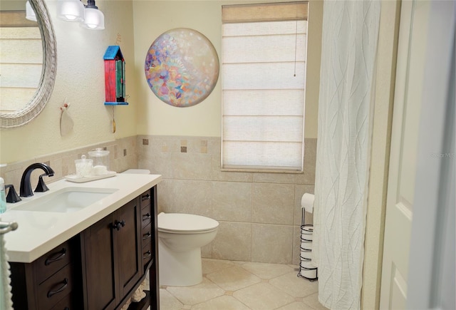 bathroom featuring a healthy amount of sunlight, tile walls, vanity, and toilet