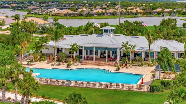 view of pool featuring a patio, a water view, and a yard