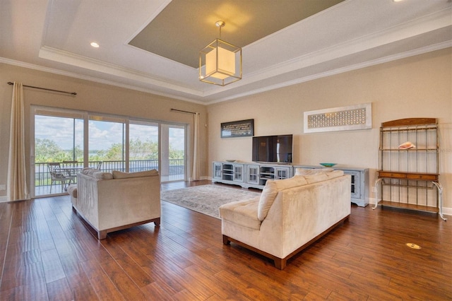 living room featuring a tray ceiling, dark wood-type flooring, and ornamental molding