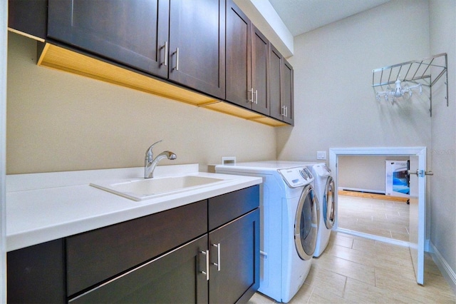 clothes washing area featuring cabinets, sink, and washing machine and clothes dryer