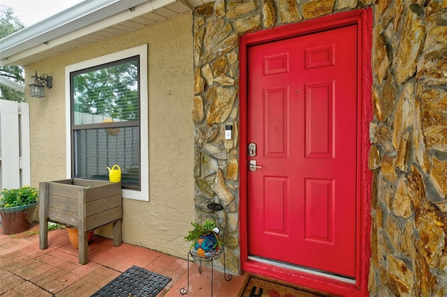 view of exterior entry featuring stucco siding and stone siding
