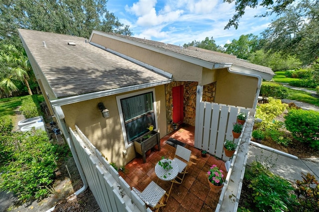 rear view of property with stucco siding and roof with shingles