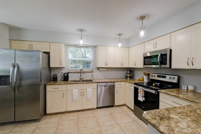 kitchen featuring light stone counters, light tile patterned floors, sink, decorative light fixtures, and appliances with stainless steel finishes