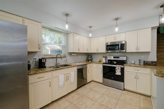 kitchen with light tile patterned floors, stone counters, a sink, stainless steel appliances, and decorative light fixtures