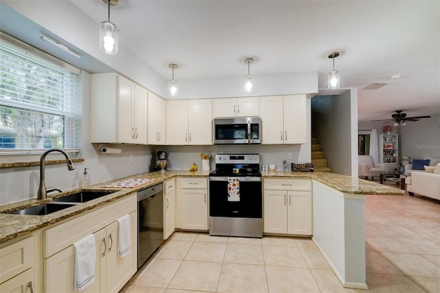 kitchen with open floor plan, a peninsula, light tile patterned floors, appliances with stainless steel finishes, and a sink