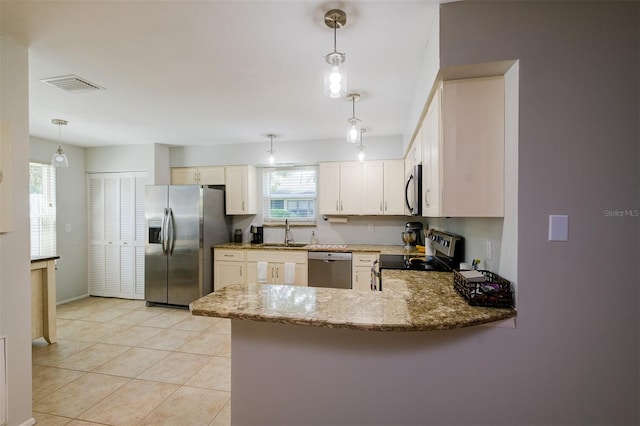 kitchen with appliances with stainless steel finishes, white cabinetry, kitchen peninsula, decorative light fixtures, and sink