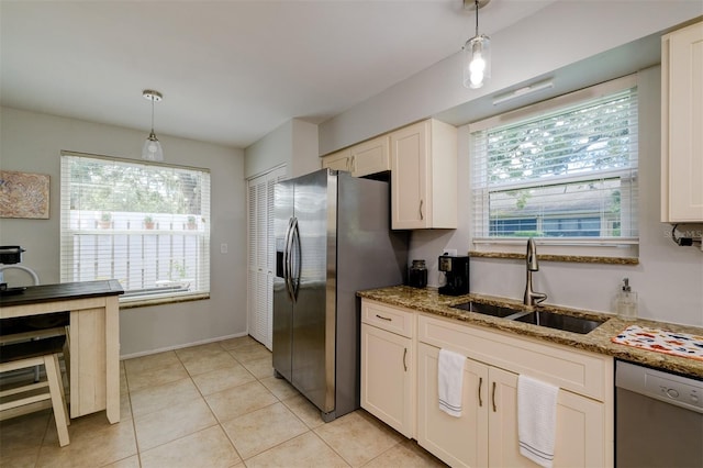 kitchen featuring stone counters, white cabinets, appliances with stainless steel finishes, pendant lighting, and a sink