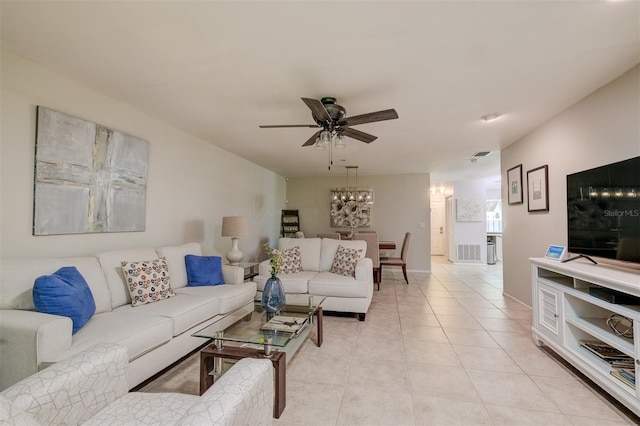 living area featuring light tile patterned floors, visible vents, and ceiling fan with notable chandelier