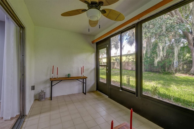 unfurnished sunroom with a textured wall and a ceiling fan