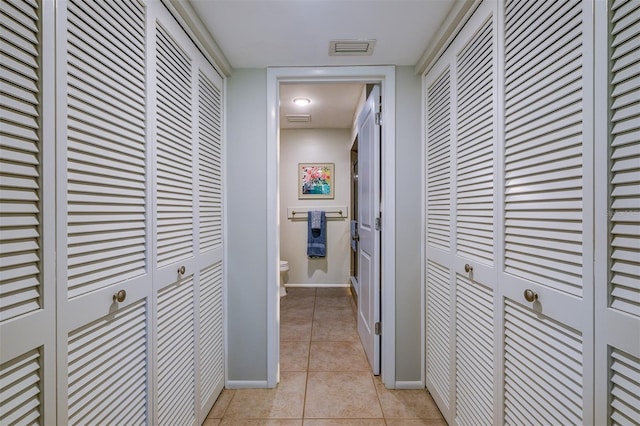 corridor featuring light tile patterned floors, baseboards, and visible vents