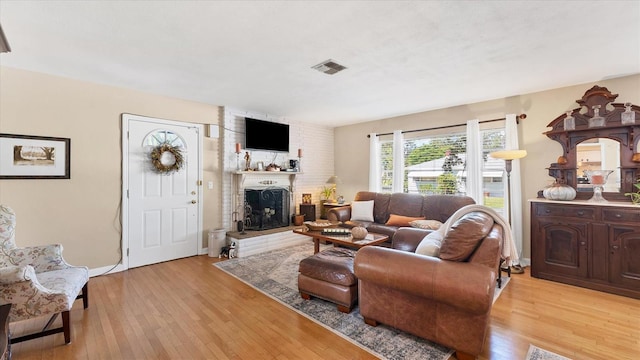 living area with visible vents, baseboards, light wood-style floors, and a fireplace
