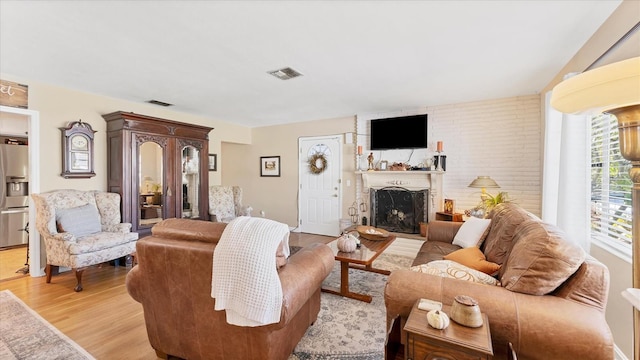 living room with a brick fireplace and light hardwood / wood-style floors