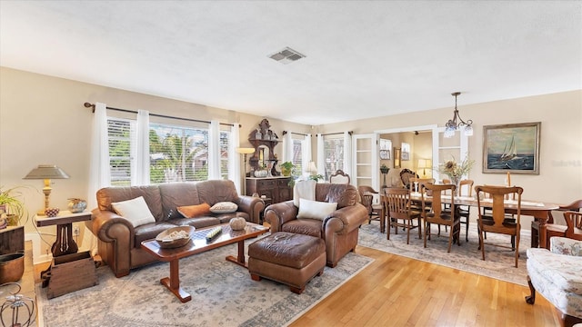 living room with visible vents, an inviting chandelier, and light wood-style flooring