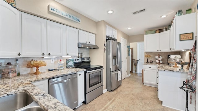 kitchen with white cabinets, appliances with stainless steel finishes, light stone countertops, and decorative backsplash