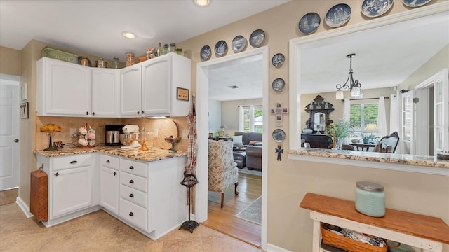 kitchen with decorative backsplash, white cabinets, light hardwood / wood-style floors, and decorative light fixtures