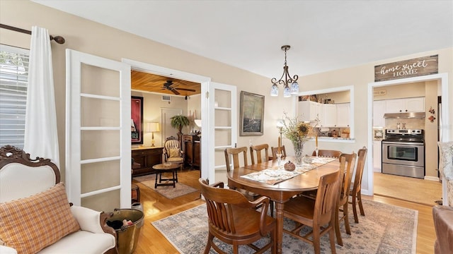 dining space with light wood-style flooring and ceiling fan with notable chandelier