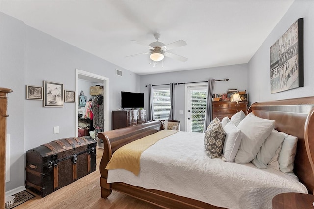 bedroom featuring access to outside, ceiling fan, a spacious closet, visible vents, and wood finished floors