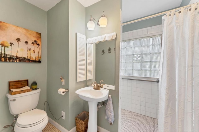full bathroom featuring baseboards, tile patterned floors, toilet, a tile shower, and a sink