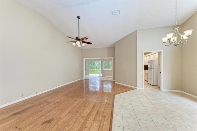 spare room with ceiling fan with notable chandelier, lofted ceiling, a textured ceiling, and light hardwood / wood-style flooring