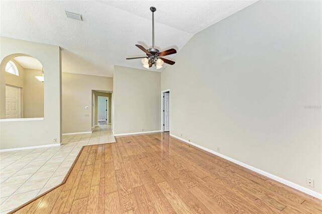 unfurnished room featuring high vaulted ceiling, light wood-type flooring, ceiling fan, and a textured ceiling