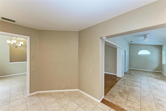 empty room featuring ceiling fan with notable chandelier and light tile patterned floors