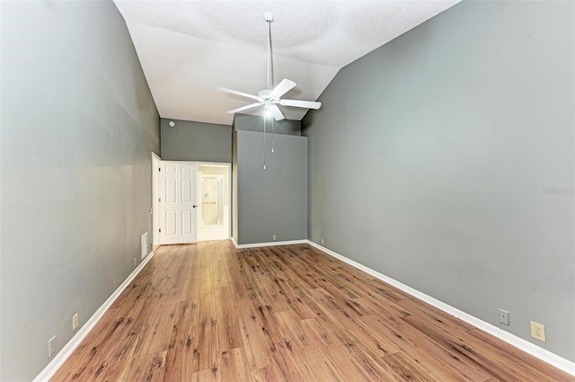 empty room featuring light wood-type flooring, a textured ceiling, vaulted ceiling, and ceiling fan