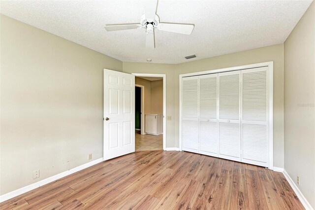 unfurnished bedroom with a closet, light wood-type flooring, ceiling fan, and a textured ceiling